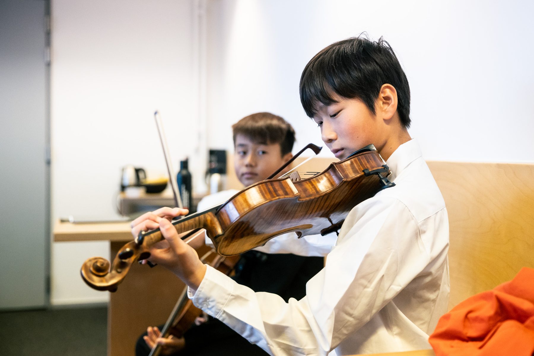 Twee jonge violisten oefenen samen backstage