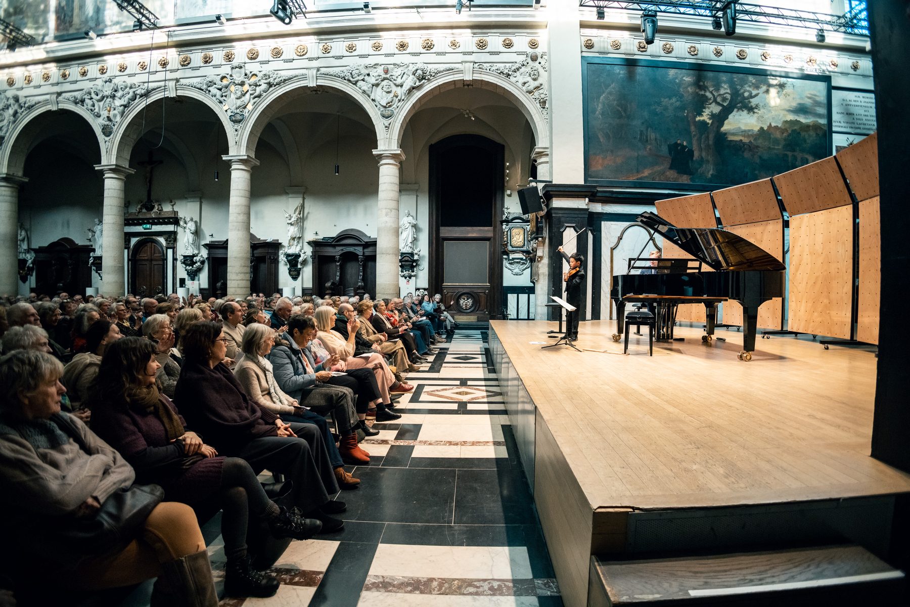 Concertzaal met vleugel en publiek tijdens een Academy-optreden